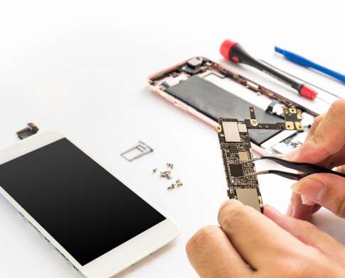 Close-up of technician hand clamping processor on smartphone logic board on smartphone component background with copy space